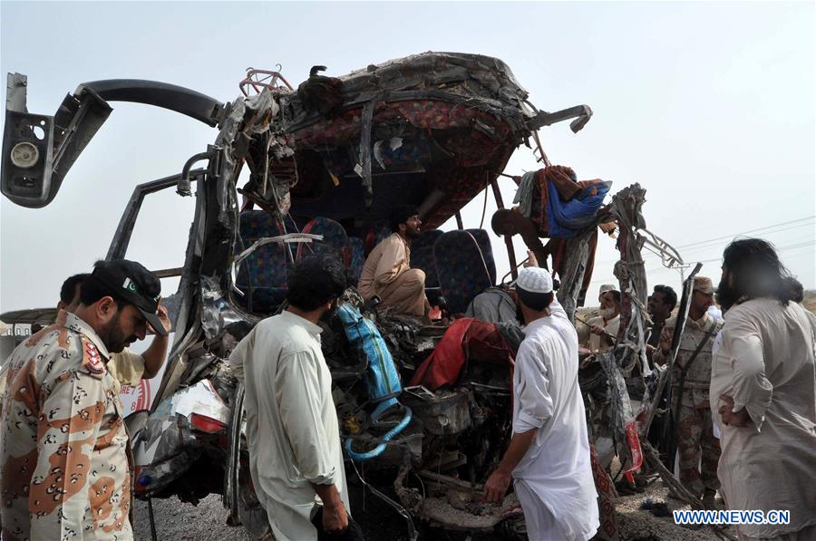 Pakistani people gather beside a damaged passenger bus at the accident site in Jamshoro, Pakistan, on Aug. 2, 2016. 