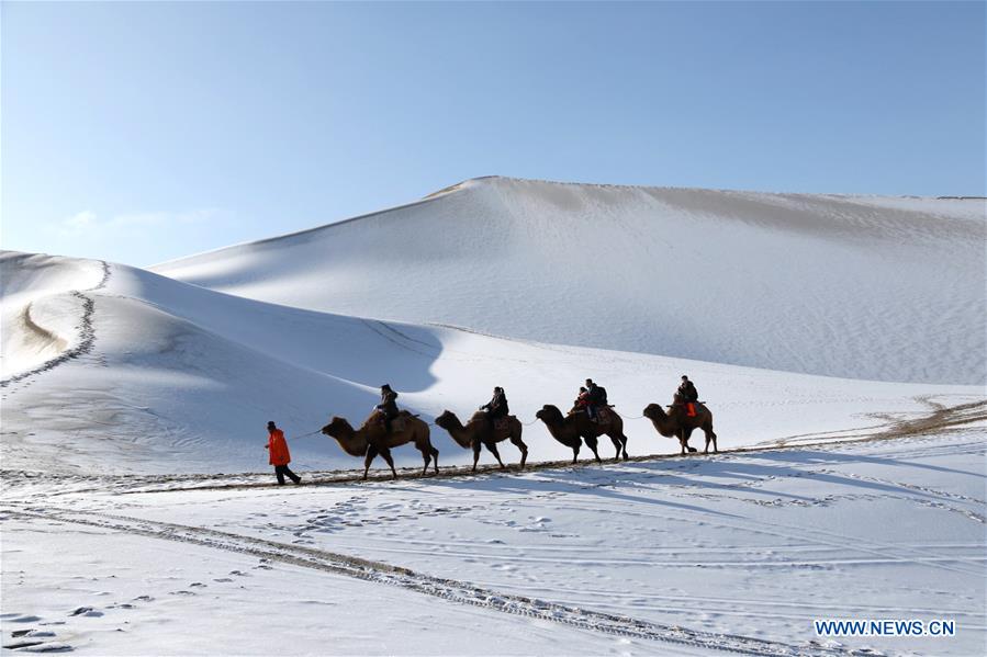 Visitors ride camels in the Crescent Spring and Singing Sand Dune scenic site of Dunhuang, northwest China's Gansu Province on Jan. 11, 2017. A recent snow made the scenic site decorated with pure white. (Xinhua/Zhang Xiaoliang) 