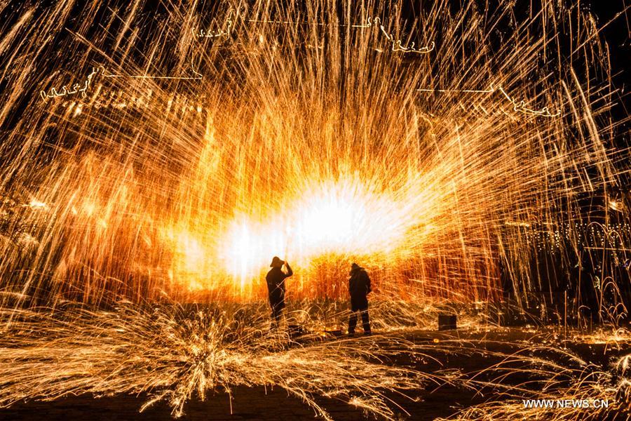 Sparks pour down as performers spray burning hot iron water to simulate display of fireworks at Neihuang County, central China's Henan Province, Feb. 1, 2017. (Xinhua/Li Gang) 