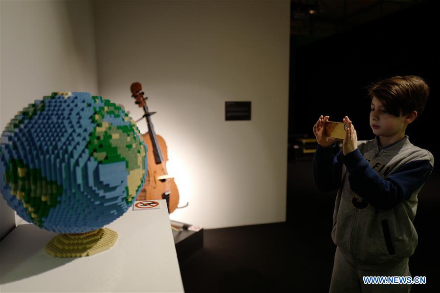 A kid takes photos of an art piece made with LEGO bricks by artist Nathan Sawaya during an exhibition in Moscow, Russia, on Feb. 28, 2017. 