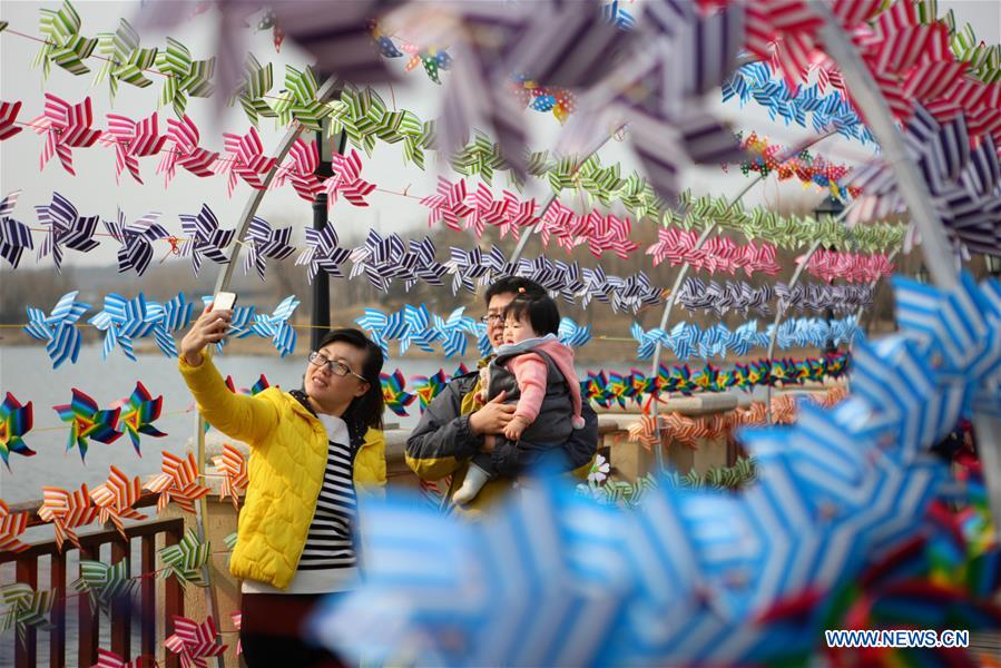 People take photos with the pinwheel decoration in Dalian, northeast China's Liaoning Province, March 11, 2017.