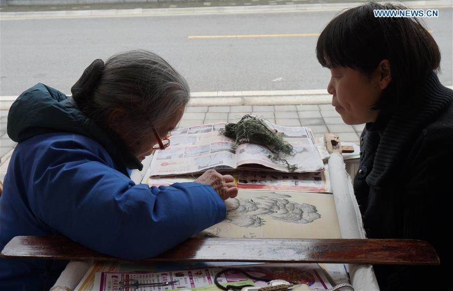 Liang Xuefang (R) watches her mother embroidering at Liangxuefang's Embroidery Studio in Suzhou, east China's Jiangsu Province, March 8, 2014. 