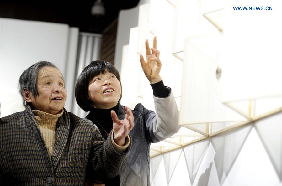 Liang Xuefang (R) introduces to her teacher Gu Wenxia, an arts and crafts master, at the exhibition of Liang's embroidery works at the Suzhou Museum in Suzhou, east China's Jiangsu Province, June 30, 2015. 
