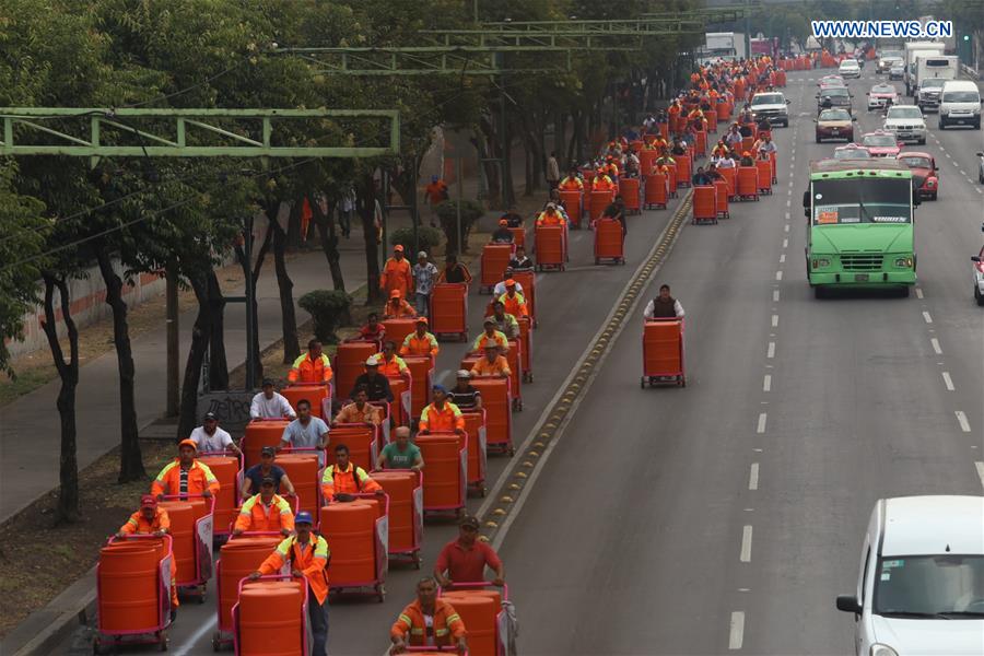 Sanitation workers walk in street after they received new trash carts in Mexico City, capital of Mexico, on March 15, 2017. 