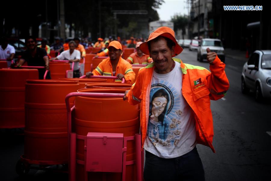 Sanitation workers walk in street after they received new trash carts in Mexico City, capital of Mexico, on March 15, 2017.