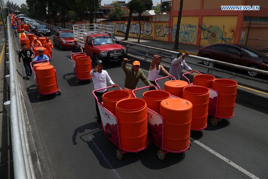 Sanitation workers walk in street after they received new trash carts in Mexico City, capital of Mexico, on March 15, 2017.