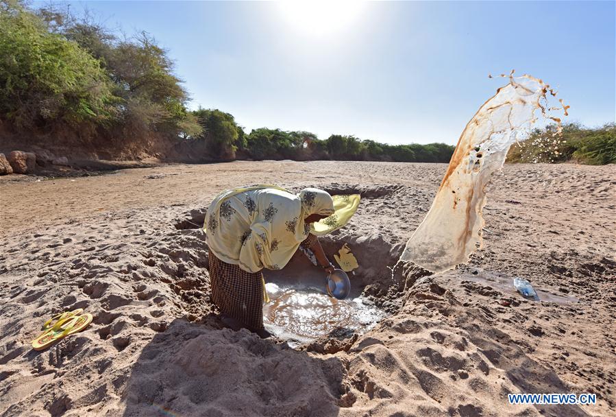A woman bowls out the unclean water from a hole in a riverbed near Doolow, a border town with Ethiopia, Somalia, March 20, 2017. 