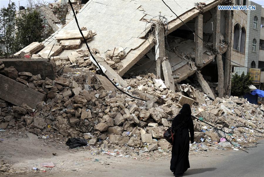 A woman walks past the rubble of a house destroyed in airstrikes at the Airport district in Sanaa, capital of Yemen, a day before the second anniversary of the military intervention in Yemen, on March 25, 2017. 