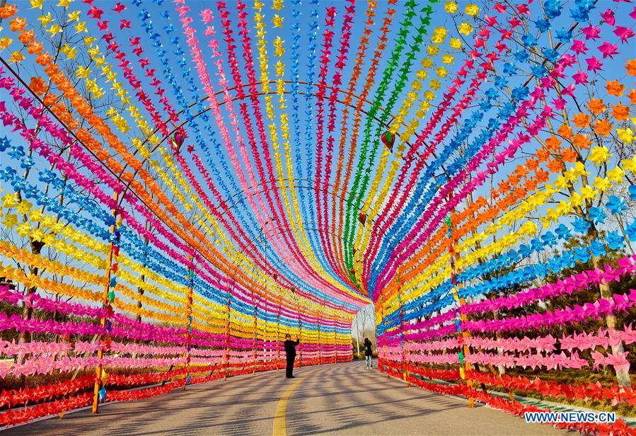 Tourists walk on a road decorated with colorful pinwheels at a Pinwheel and Kite Festival in Tangshan, north China's Hebei Province, March 27, 2017.