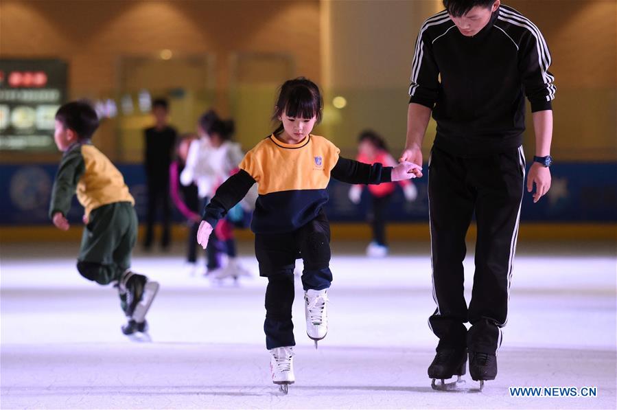 A coach (R) teaches a girl skating in the Century Star Rink in Kunming, capital of southwest China's Yunnan province, March 16, 2017.