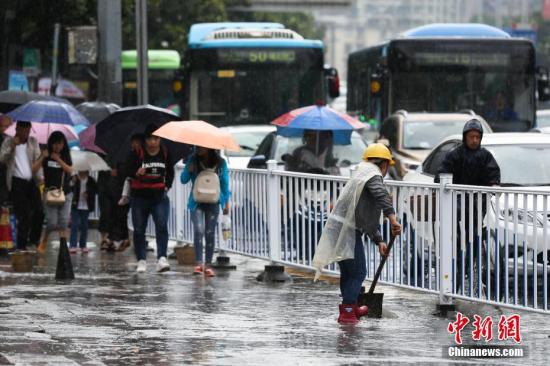 6月12日，貴陽持續降雨造成貴陽市多處路段嚴重積水，市民出行受阻。圖為貴陽市環衛工人清理路面積水。 黃芷昕 攝