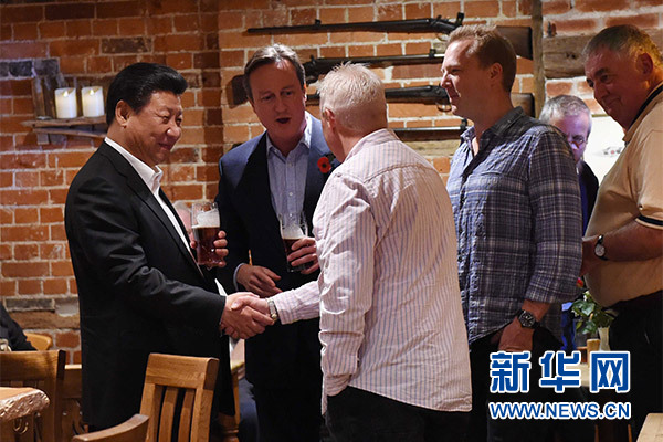 這是習近平與卡梅倫飲啤酒，並同當地民眾交談。新華社記者 饒愛民 攝