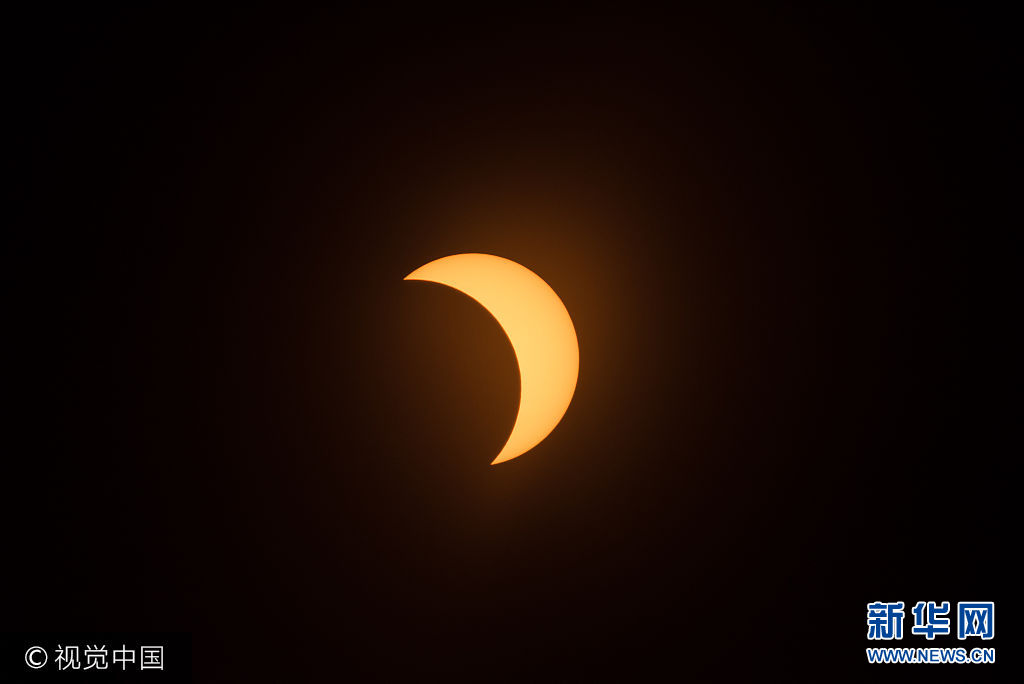 當地時間2017年8月21日，美國紐約，民眾在戶外觀看日全食奇觀。***_***NEW YORK, NY - AUGUST 21:  The solar eclipse is seen at Liberty Island in on August 21, 2017 in New York City. While New York was not in the path of totality for the solar eclipse, around 72 percent of the sun was covered by the moon during the peak time of the partial eclipse.  (Photo by Noam Galai/WireImage)