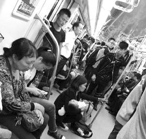 女子抱宝宝坐地上 车厢内有座的人各忙各的