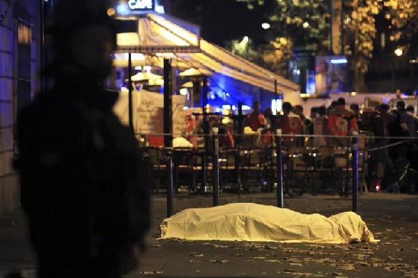 A lifeless body covered under sheet lies on the pavement near the Bataclan theater after a shooting in Paris, Friday Nov. 13, 2015. French President Francois Hollande declared a state of emergency and announced that he was closing the country's borders. 