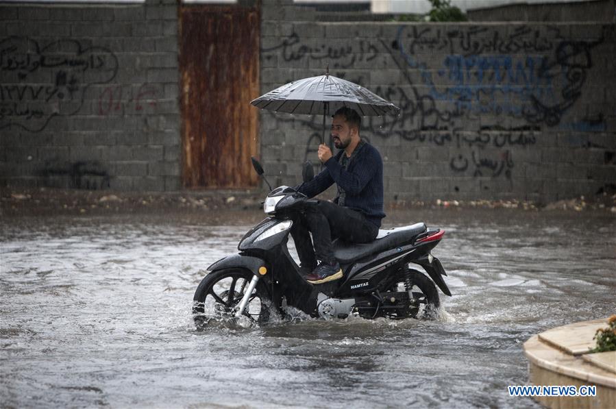 People walk through flooded street during heavy rain in Iran Xinhua