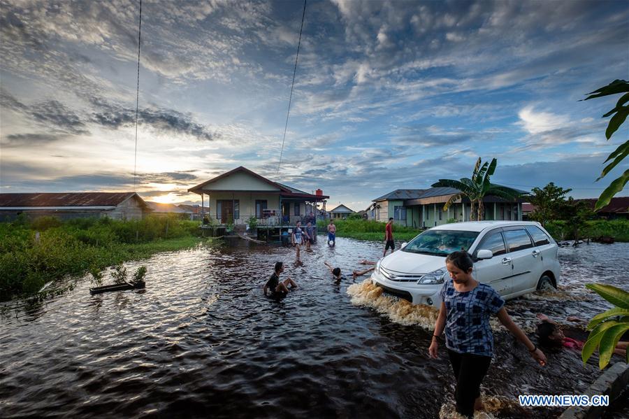 people walk in flood water at mendawai village in indonesia