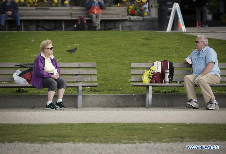 people observe social distancing at english bay in vancouver