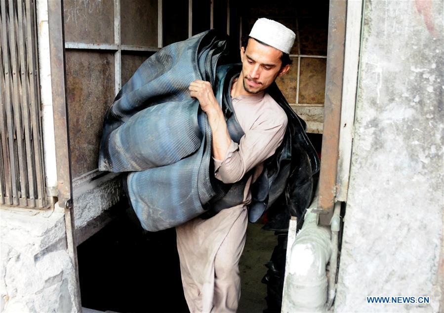 Workers make traditional shoes at shop in Pakistan's Peshawar Xinhua