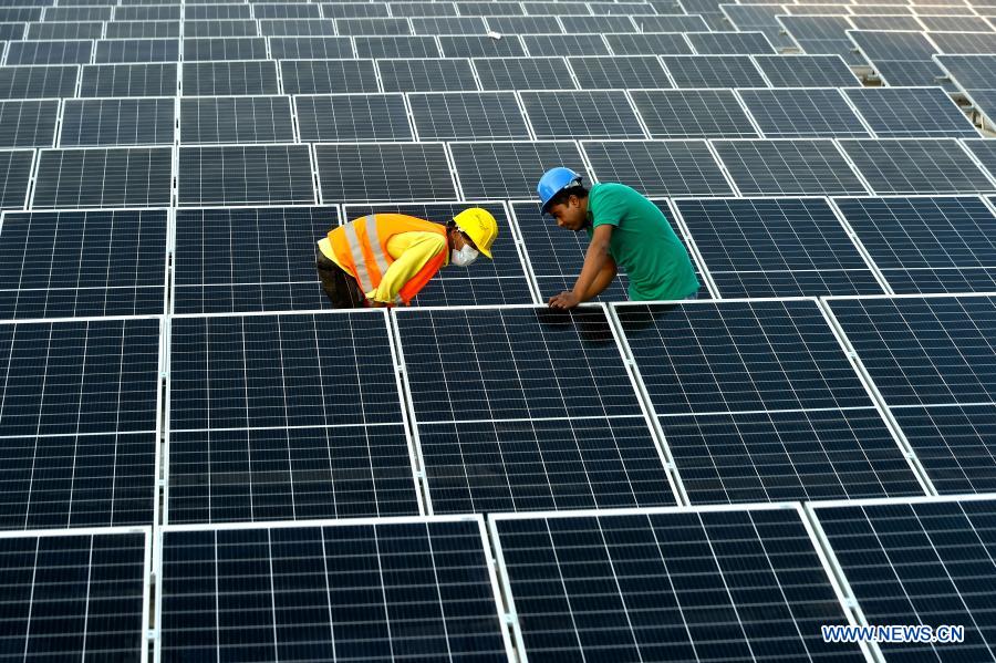 Supervisors monitor installation process of solar panels on factory