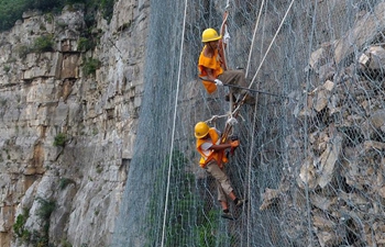 Workers work on cliff to ensure railway safety in C China's Henan