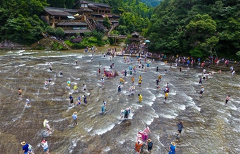 People cool themselves in shallow water at scenic spot in China's Fujian