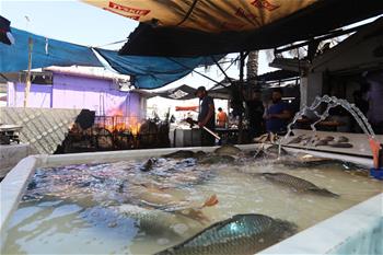 Men make grilled fish at shop in Baghdad, Iraq