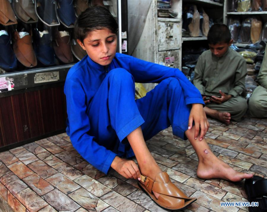 Workers make traditional shoes at shop in Pakistan's Peshawar Xinhua
