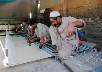 Pakistani workers make carpet at carpet factory in Peshawar