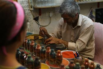 Palestinian craftsman works on sand art bottle at souvenir shop