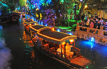 People enjoy night view of ancient river course on boat in China's Zhejiang