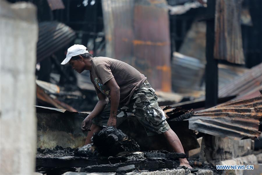 A man looks for belongings in his burnt house after a fire at a residential area in Manila, the Philippines, June 6, 2016. 