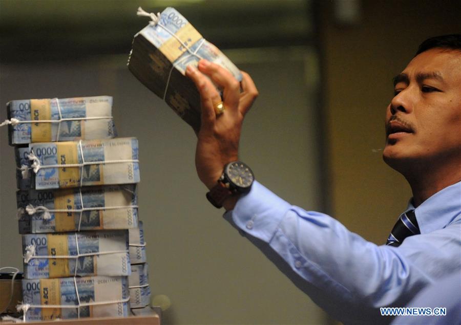 A staff member of Indonesia's central bank checks some Indonesian currency rupiah cash before distributing them from Indonesia's central bank to branches in Jakarta, Indonesia, June 6, 2016. 