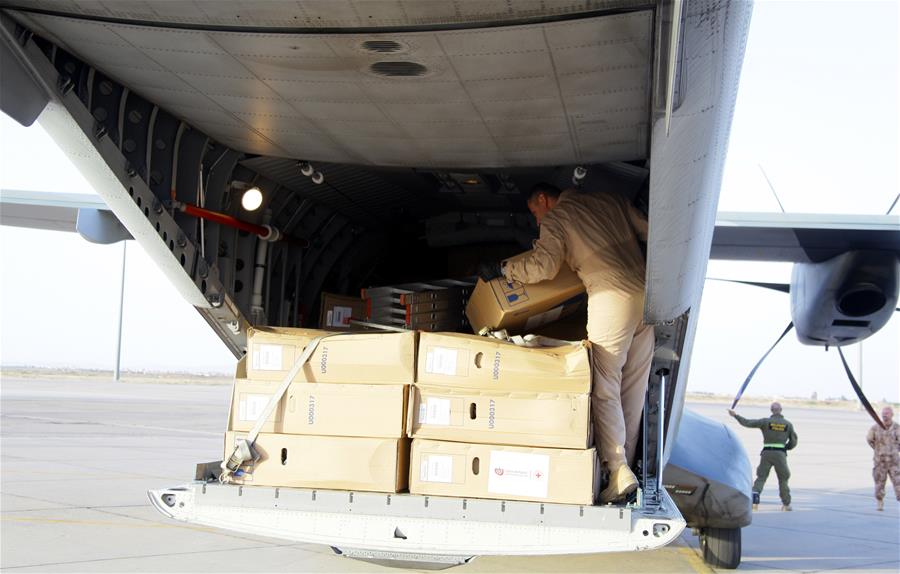 A flight crew member helps download packages of relief aid from a Czech aircraft at International Airport of Damascus, capital of Syria, on June 7, 2016. 