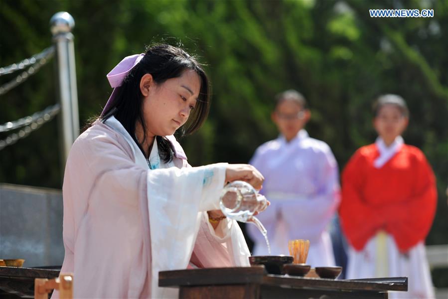 A woman in Han dress performs tea ritual during a sacrificial ceremony for Qu Yuan, a patriotic poet who drowned himself before his state fell to the invasion of the enemy during the Warring States Period (475-221 BC), in Lanzhou, capital of northwest China's Gansu Province, June 9, 2016. 