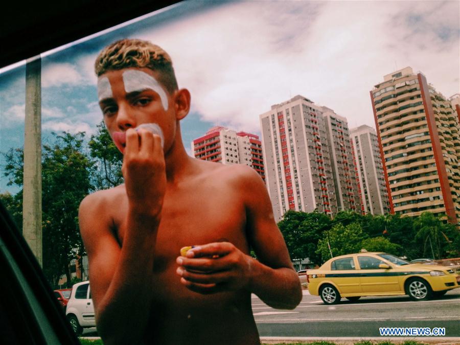 This file photo shows a young street performer puting on makeup in front of the window of a vehicle in Rio de Janeiro, Brazil on Feb. 19, 2015.