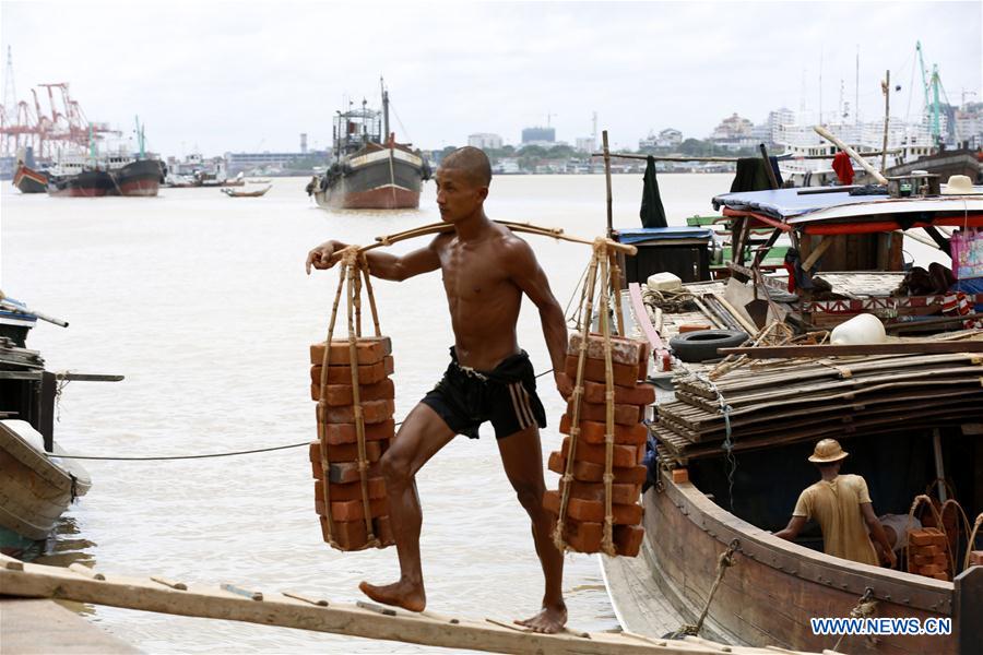A labor carries bricks at a jetty on the outskirts of Yangon, Myanmar, June 16, 2016.