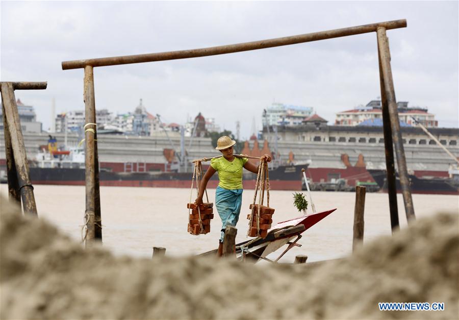 A labor carries bricks at a jetty on the outskirts of Yangon, Myanmar, June 16, 2016.