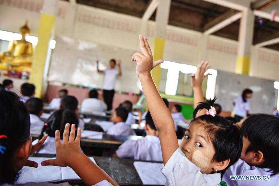 A teacher (1st L) revises homework for students at a school dedicated for the children of Myanmar migrant workers set inside Wat Tepnorrarat in Mahachai of Samut Sakhon Province, central Thailand, June 16, 2016. 