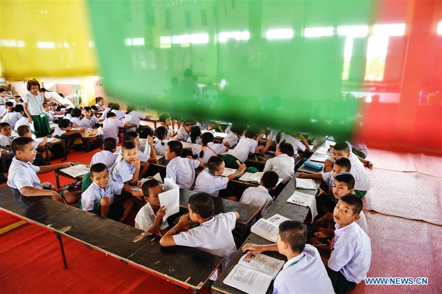 A teacher (1st L) revises homework for students at a school dedicated for the children of Myanmar migrant workers set inside Wat Tepnorrarat in Mahachai of Samut Sakhon Province, central Thailand, June 16, 2016. 