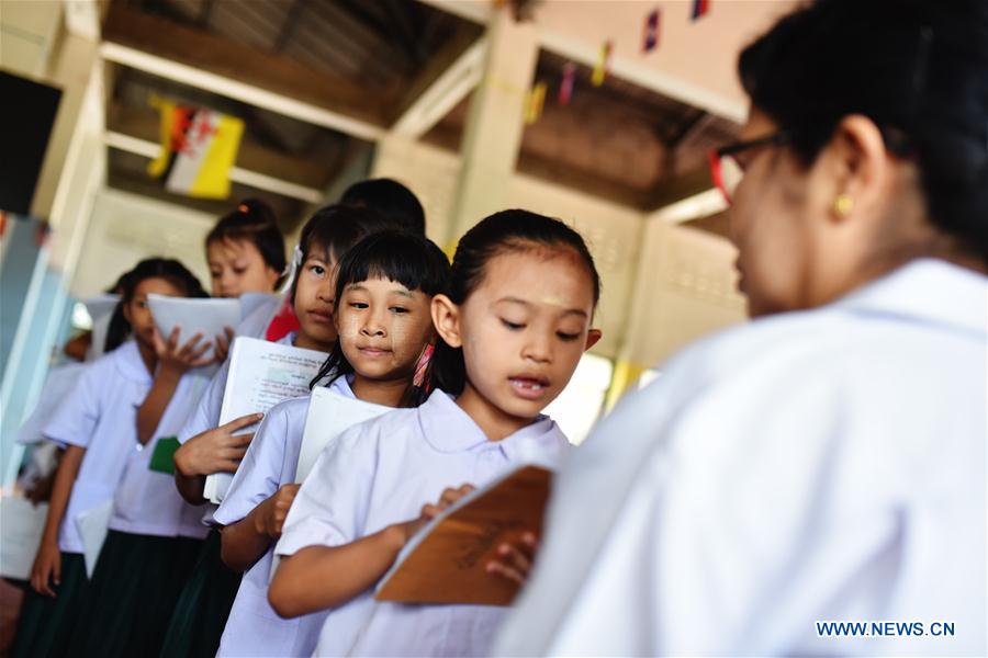 A teacher (1st L) revises homework for students at a school dedicated for the children of Myanmar migrant workers set inside Wat Tepnorrarat in Mahachai of Samut Sakhon Province, central Thailand, June 16, 2016. 