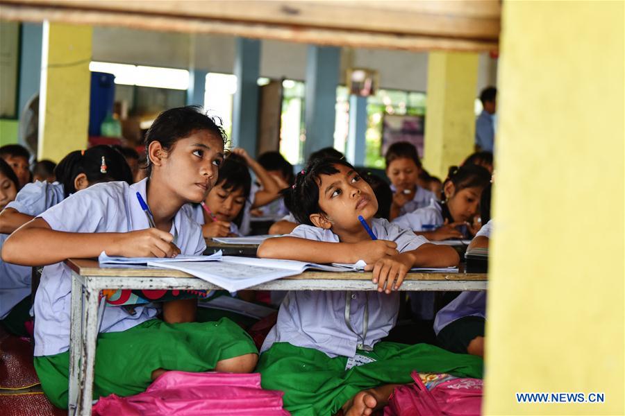 A teacher (1st L) revises homework for students at a school dedicated for the children of Myanmar migrant workers set inside Wat Tepnorrarat in Mahachai of Samut Sakhon Province, central Thailand, June 16, 2016. 