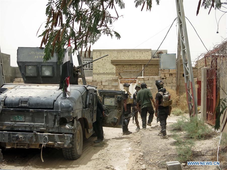 Two Iraqi army soldiers walk near a building destroyed in battles in Shuhada district in southern Fallujah, some 50 km west of the Iraqi capital of Baghdad on June 16, 2016, after the army retakes the district from the Islamic State(IS). 