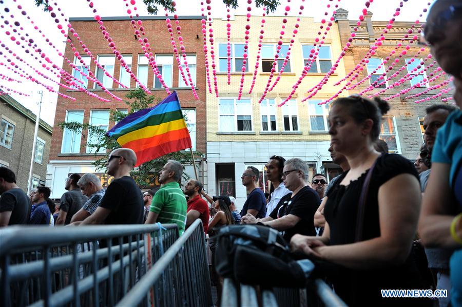 People hold candles and a torch to pay tribute to Orlando nightclub shooting victims, in downtown Montreal, Canada, on June 16, 2016.