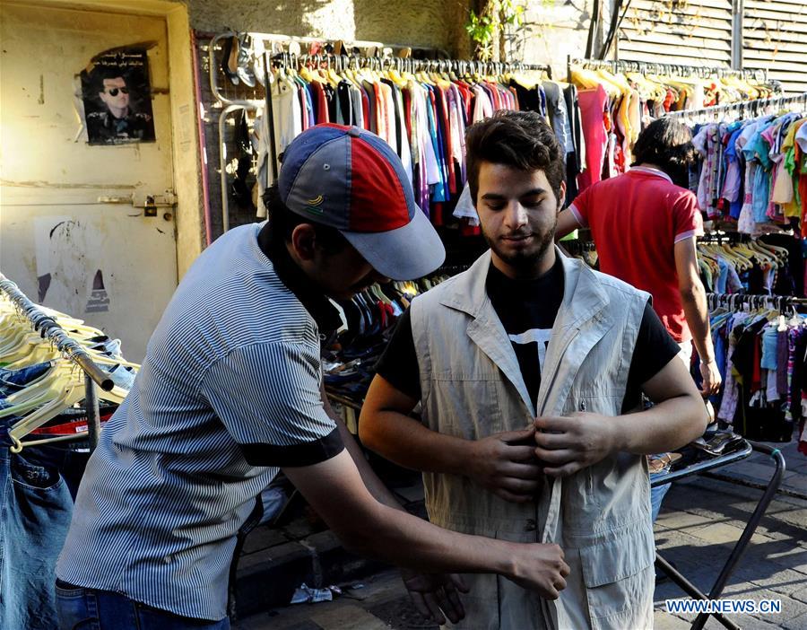 A Syrian vendor leans on a stall of second-hand clothes in Damascus, capital of Syria, on June 28, 2016. 