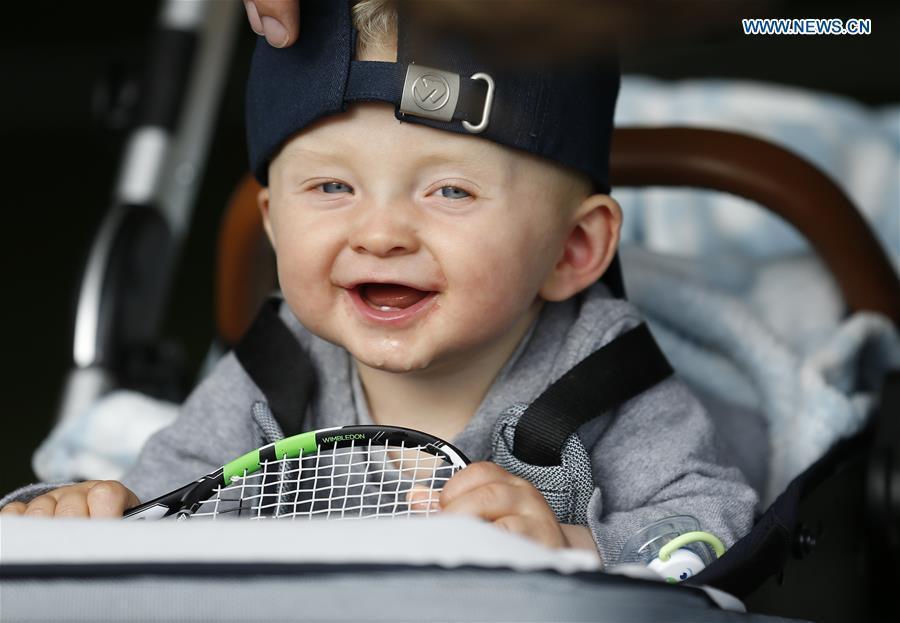 Photo taken on June 30, 2016 shows a baby playing with a toy tennis racket at the Wimbledon Tennis Championships in London, Britain on June 30, 2016. 