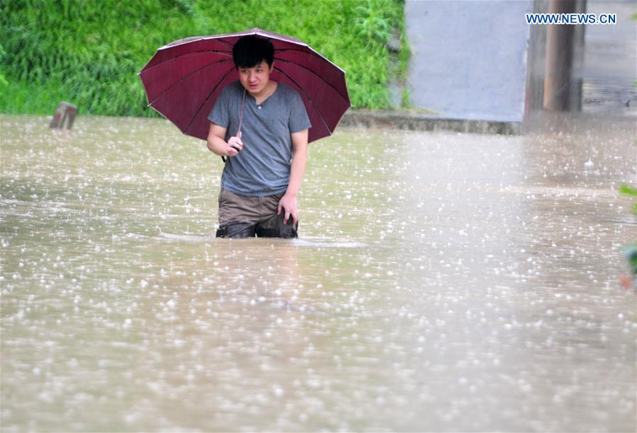 A man walks on a flooded road in Jiujiang City, east China's Jiangxi Province, July 2, 2016. 