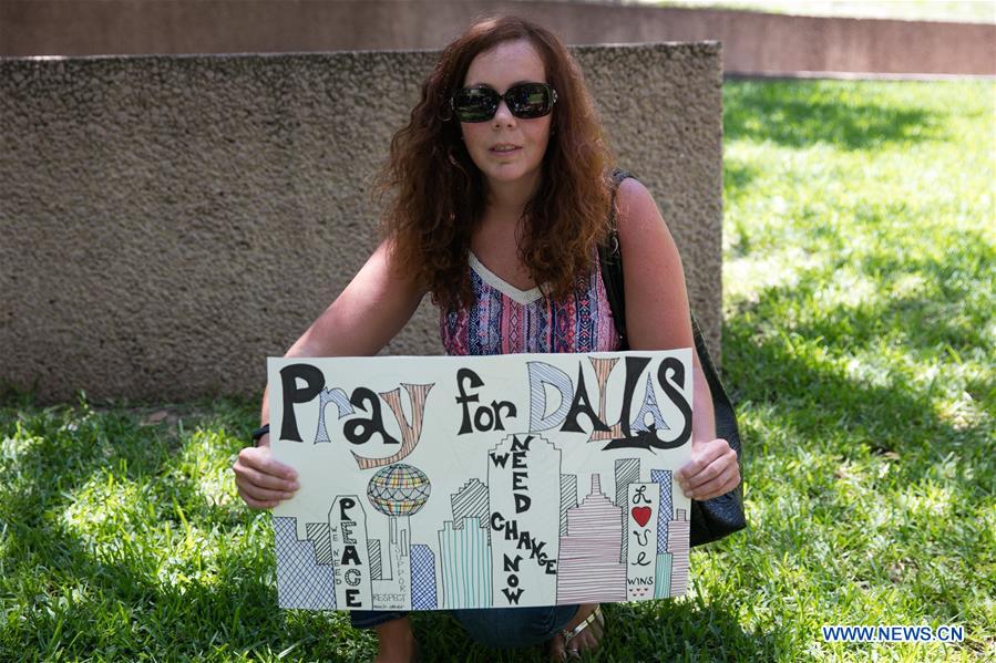A woman holds a placard during a mourning for the police personnel killed by snipers in Dallas, the United States, July 8, 2016.
