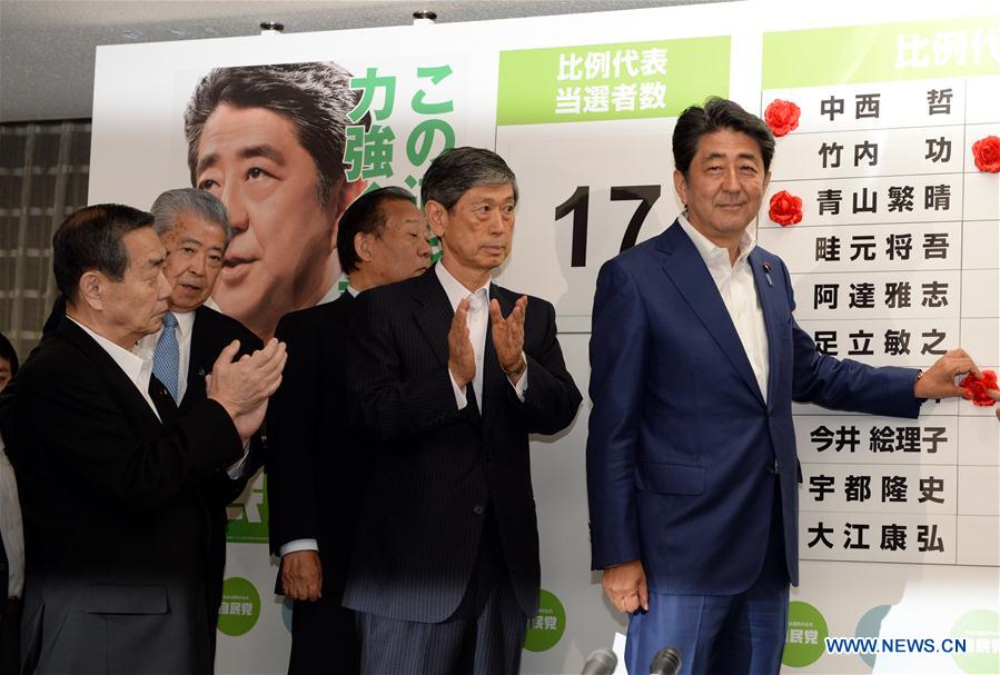 Japan's Prime Minister and leader of the ruling Liberal Democratic Party (LDP) Shinzo Abe (1st R) puts a rosette on the name of a candidate who is expected to win in the upper house election, at the LDP headquarters in Tokyo, Japan, July 10, 2016. 