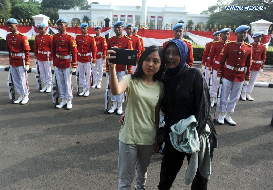 People take selfies during a show of the Indonesian Guard of Honor in front of the Presidential Palace in Jakarta, Indonesia, July 17, 2016. 